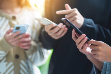 Group of young people using and looking at mobile phone together