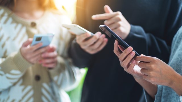 Group of young people using and looking at mobile phone together
